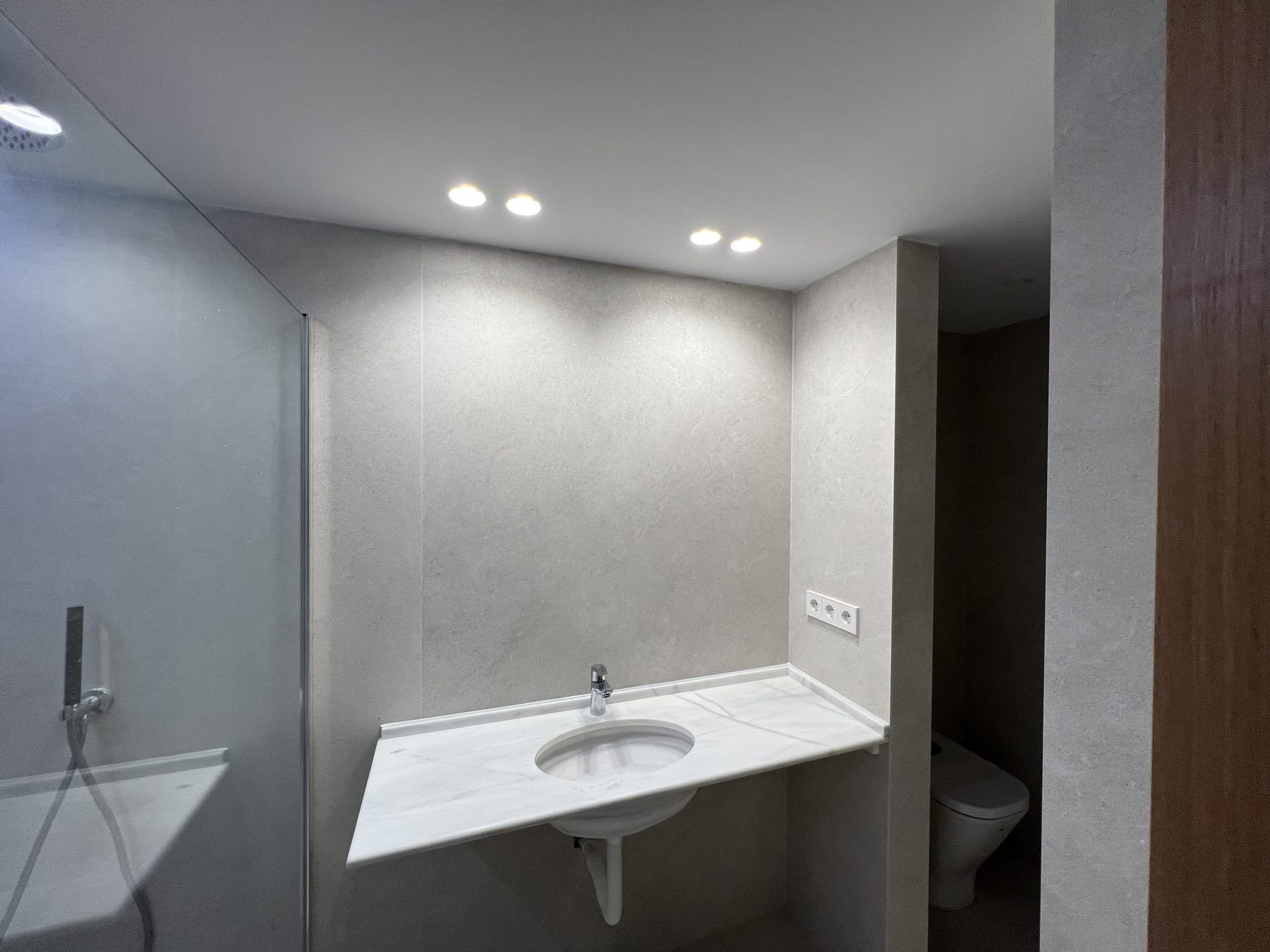 Baño principal con encimera de mármol y microcemento.