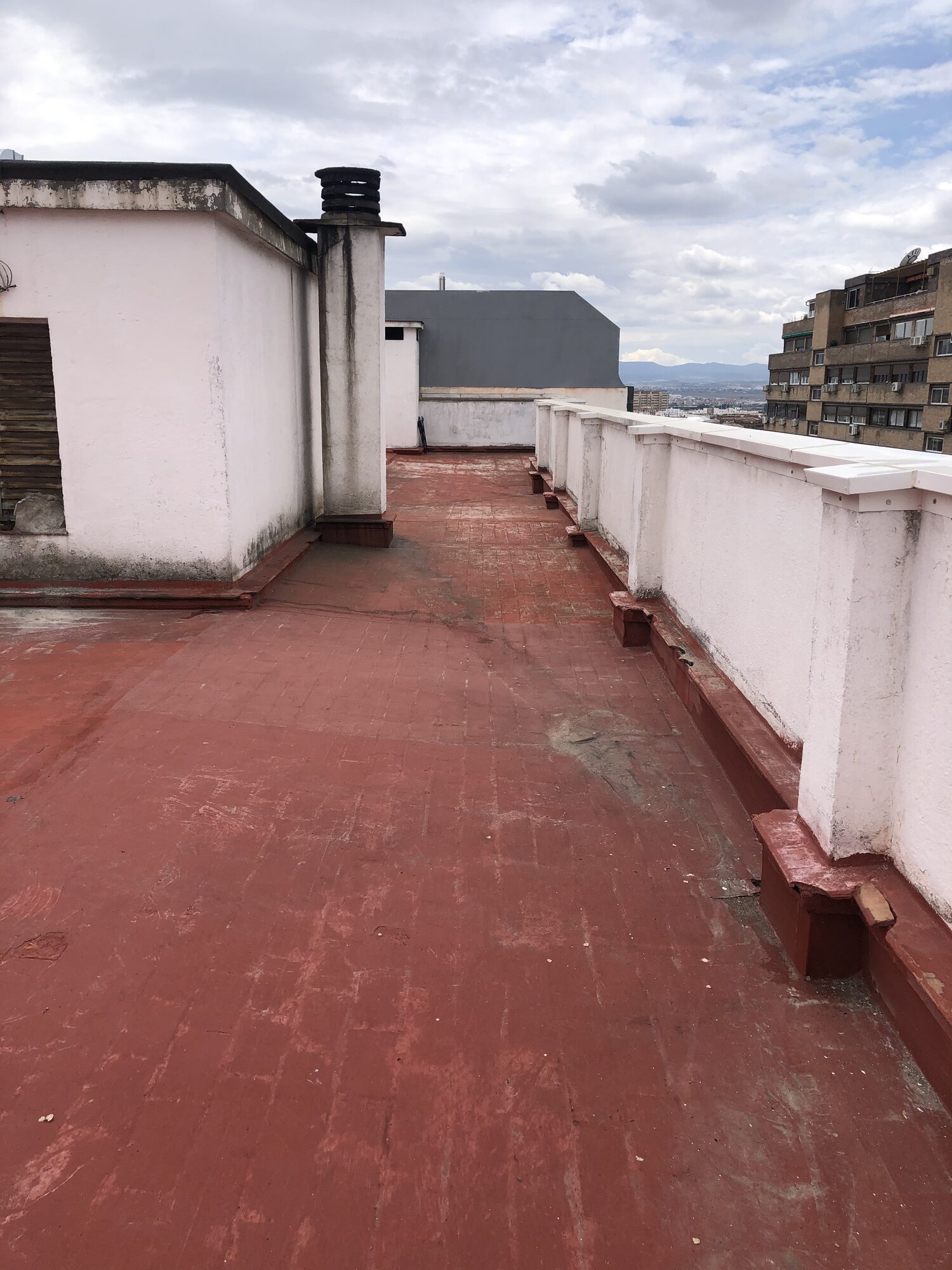 Zona comunitaria transitable con impermeabilización envejecida antes de la intervención.