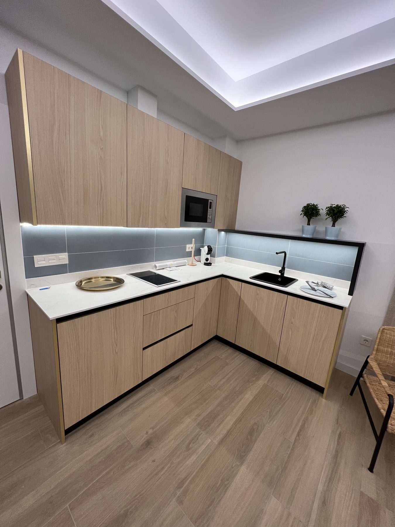 Cocina abierta en tonos claros con encimera blanca.