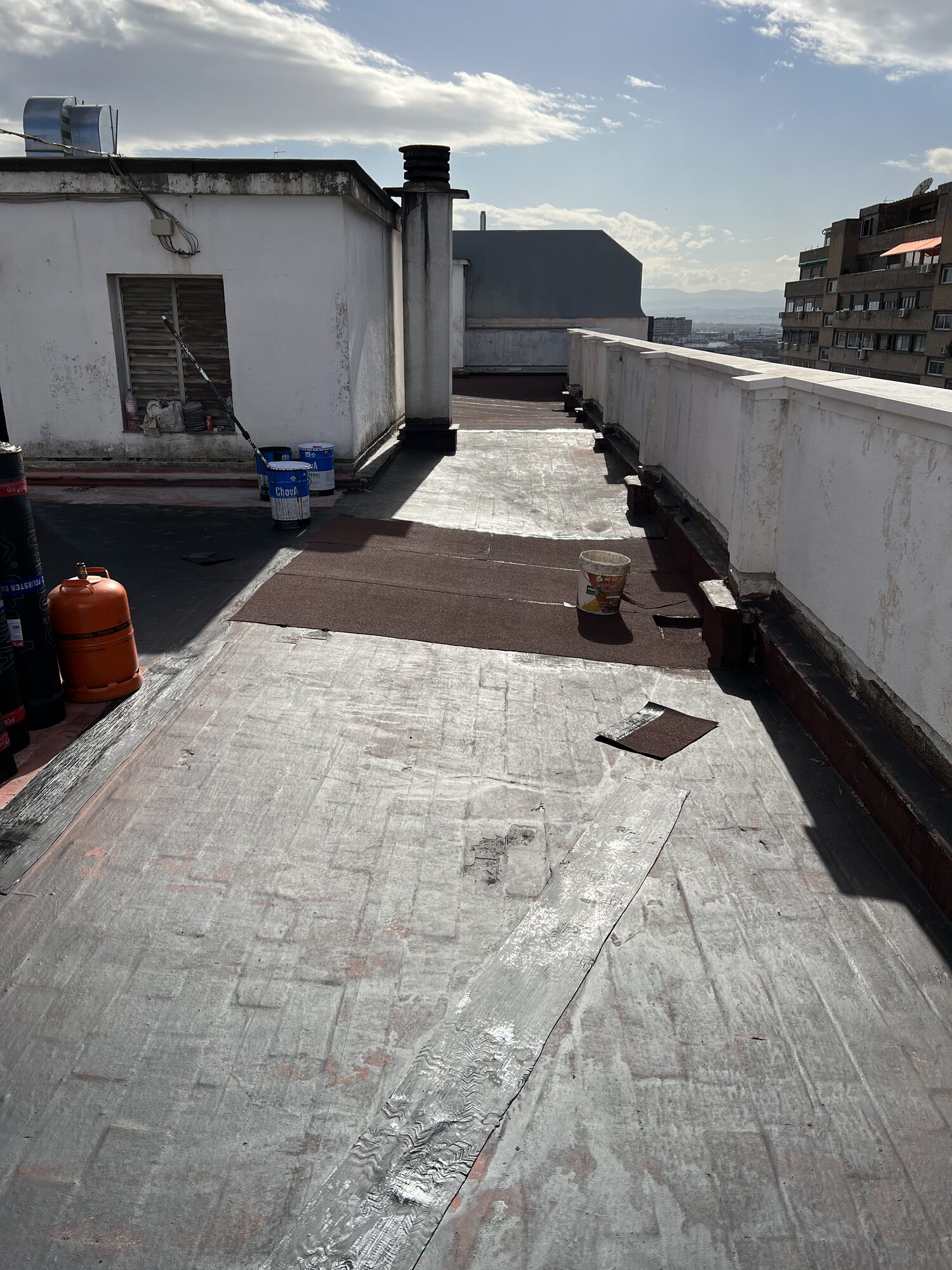 Preparación del material y ejecución de la nueva lámina asfáltica autoprotegida en la zona comunitaria.